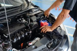 Mechanic inspecting a car engine for potential issues.