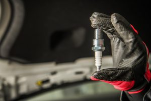 Close-up of mechanic inspecting a spark plug, a potential cause of engine losing power.