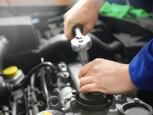 Mechanic using engine reconditioning equipment to tighten a bolt on a car engine.